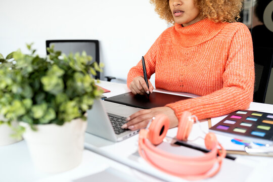Black woman using laptop in office.