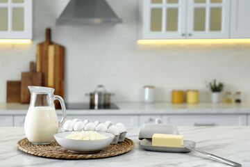 Fototapeta na wymiar Different dairy products and eggs on white table in modern kitchen. Space for text
