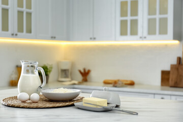 Different dairy products and eggs on white table in modern kitchen. Space for text
