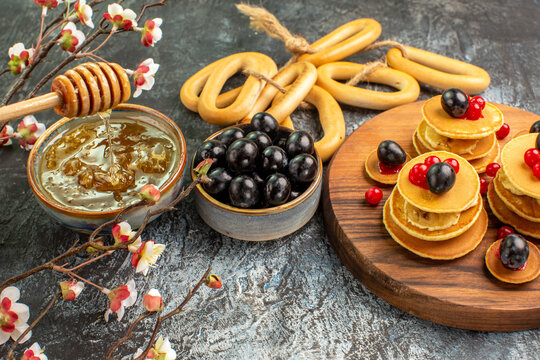 Ring-shaped cookies fruit pancakes near honey in a bowl and black cherries with cookies stock image