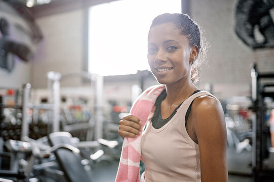 Afro woman standing in gym with towel.