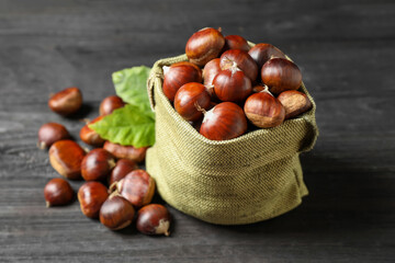 Fresh sweet edible chestnuts on black wooden table