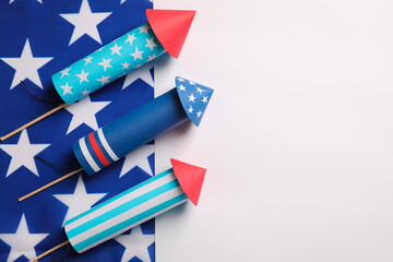 Firework rockets and USA flag on white background, flat lay with space for text. Festive decor