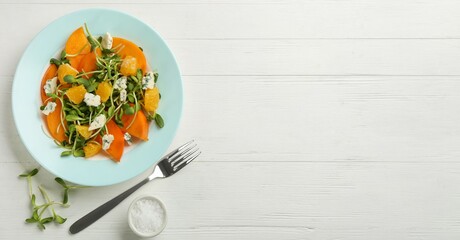 Delicious persimmon salad served on white wooden table, flat lay. Space for text