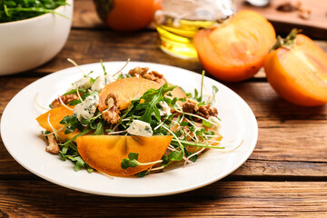 Delicious persimmon salad served on wooden table, closeup