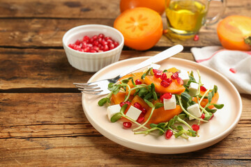 Delicious persimmon salad served on wooden table, closeup