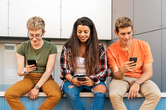 Three teenagers looking at their mobile phones.