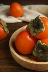 Tasty ripe persimmons on wooden table, closeup