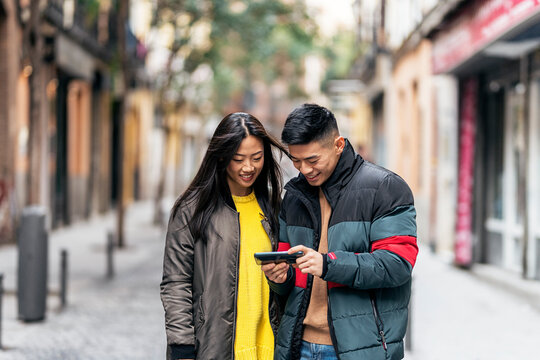 Chinese couple looking at smartphone on a street.