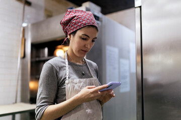 Woman looking at smartphone in bakery.