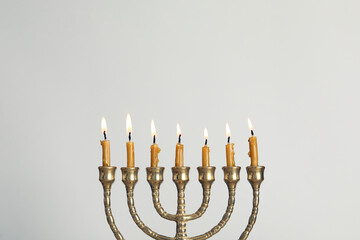 Golden menorah with burning candles on light grey background, space for text