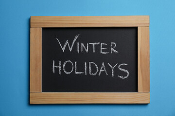 Obraz premium Chalkboard with words Winter Holidays on light blue background, top view