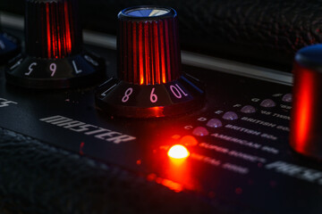 Detail of an amplifier for electric guitar with red lights - obrazy, fototapety, plakaty