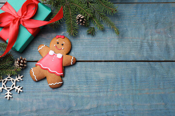 Flat lay composition with gingerbread girl on blue wooden table, space for text