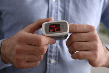 Man measuring oxygen level with modern fingertip pulse oximeter, closeup