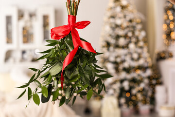 Mistletoe bunch with red bow hanging in room decorated for Christmas