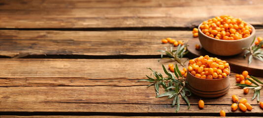 Fototapeta premium Fresh ripe sea buckthorn on wooden table, space for text. Banner design