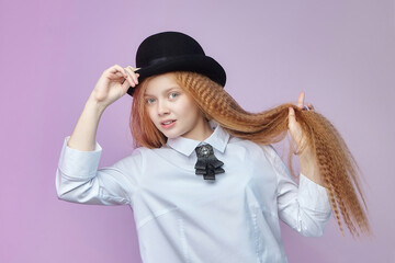 teenage girl with long red hair and a hat. photo session in the Studio on a pink background