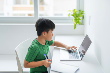 An asian schoolboy is studying at home.