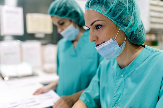 Female doctors in uniforms and masks using computer at table