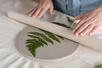 Craftswoman creating natural pattern on clay