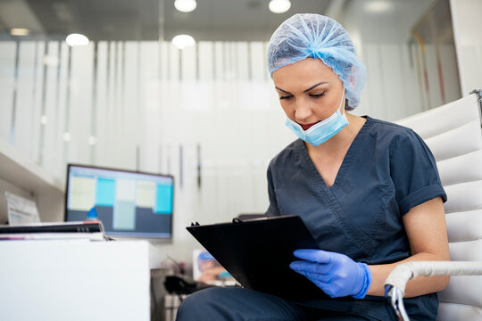 Male Doctor In Uniform And Mask Holding Documents