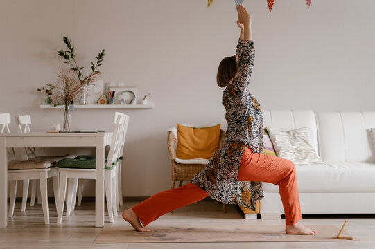 Active woman in Crescent Lunge yoga pose training at home