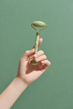 The girl holds a jade face roller in her hand