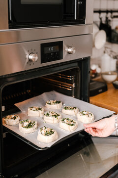 Crop woman putting buns into oven