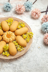 Fototapeta na wymiar a view of a plate of cookies with pale blue and pink flowers around it on marble background