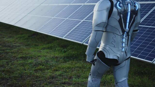 Smart AI cyborg prototype walking on solar field to control sustainable green energy development. Solar station. Futuristic development. Science fiction.