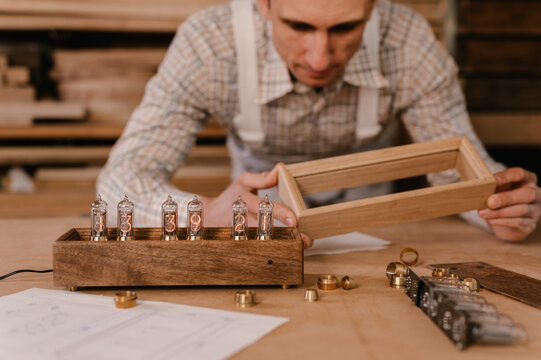 Crop craftsman examining frame for handmade clock