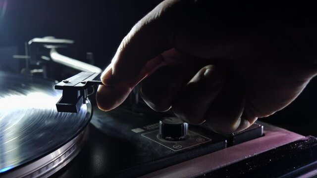 hands placing the vintage turntable on a spinning vinyl record. the vinyl record is spinning. the needle plays on a vintage vinyl record