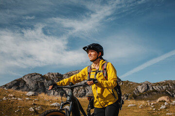 Smiling woman walking with electric mountain bike against mountain at Somiedo Natural Park, Spain