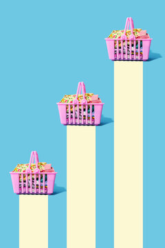 Studio shot of three pink shopping baskets filled with clothing leaving yellow trails