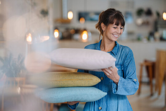 Female entrepreneur holding pillows while standing in cafe