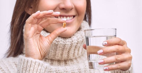 Happy woman with fish oil capsule or vitamin D supplement. Taking omega 3 or D3