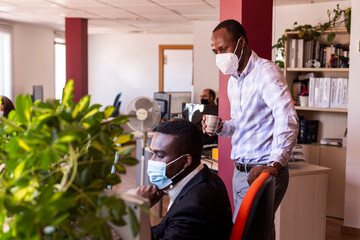 Male business professionals in protective face masks working at office during  COVID-19 crisis