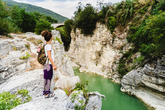 Woman with backpack admiring view while standing on mountain at Marmitte Dei Giganti, Marche, Italy