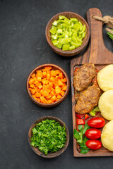 Vertical view of dinner background with tasty cutlets vegetables and greens on dark background