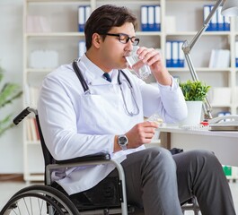 Naklejka na ściany i meble Disabled doctor on wheelchair working in hospital