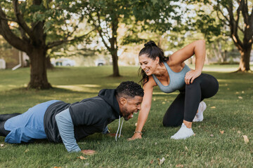 Smiling woman looking at man doing push up at backyard