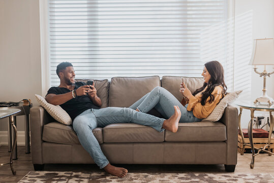 Couple using mobile phone while sitting on sofa at home
