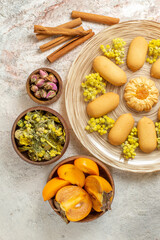 an overhead photo of a plate of cookies and cinnamon sticks and dry flowers and palm