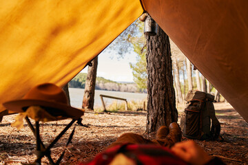 Low section of bushcrafter lying down under camping tent