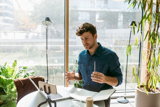 Confident young businessman discussing on video call through smart phone at table in cafe