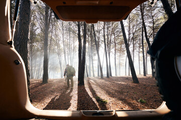 Buscrafter hiking in forest seen from car trunk