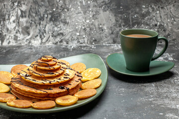 Side view of pancake decoration on a green plate and a cup of coffee on gray background