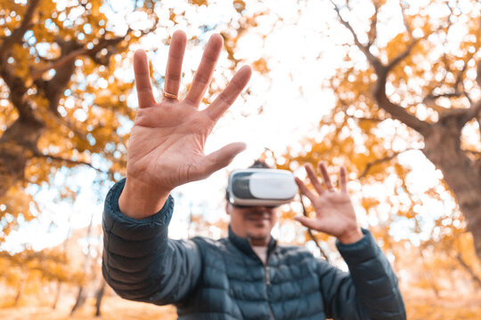Man gesturing while wearing virtual simulator standing in park
