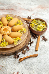 a plate of delicious cookies on wooden platter and diffenert types of dry herbs on marble ground